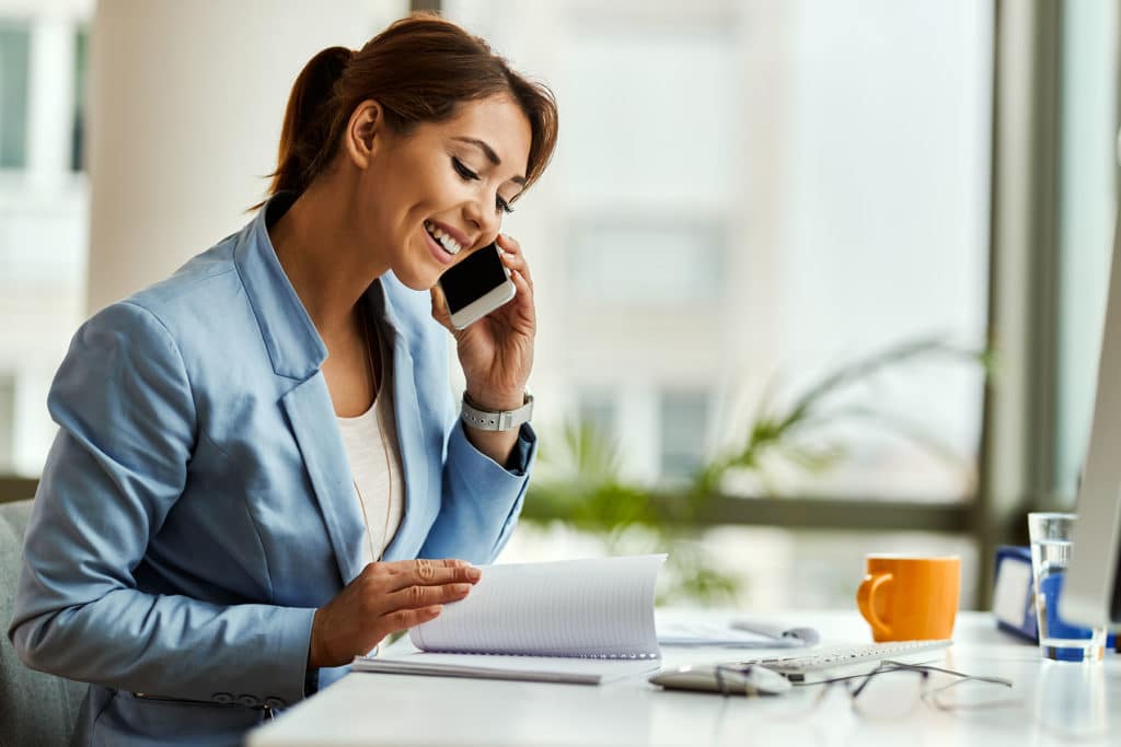 Happy,businesswoman,talking,on,mobile,phone,while,analyzing,weekly,schedule