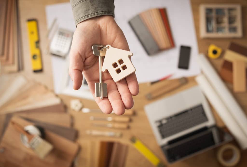 Real Estate Small House and Key in Investor's Hand