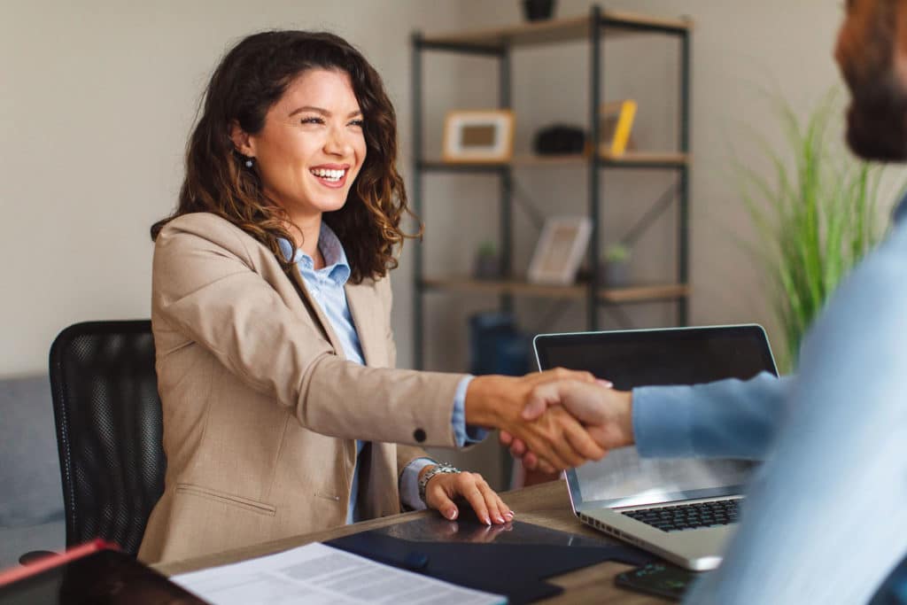 Investor woman speaking with a financial advisor about her investment strategy and shaking his hand.