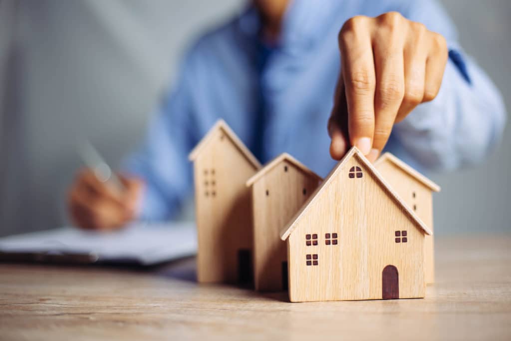 Businessman,choosing,mini,wood,house,model,from,model,on,wood