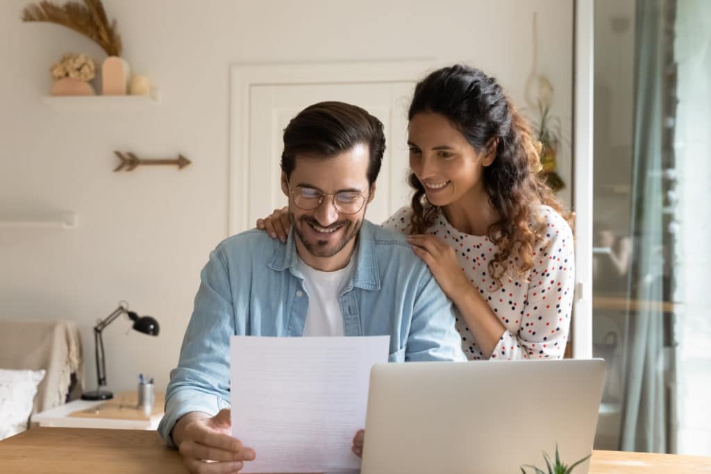 Happy,young,wife,embrace,shoulders,of,beloved,husband,reading,official